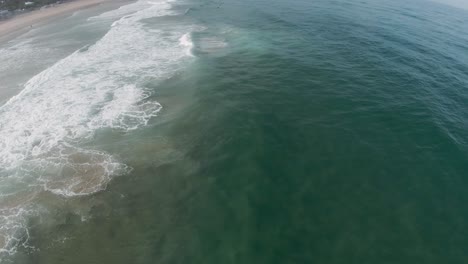 Ocean-waves-crash-and-spread-white-wash-on-sandy-shore-on-sunny-day