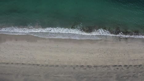 Aerial-top-down-shot-of-sandy-beach-and-turquoise-clear-water-of-ocean-reaching-ICELAND