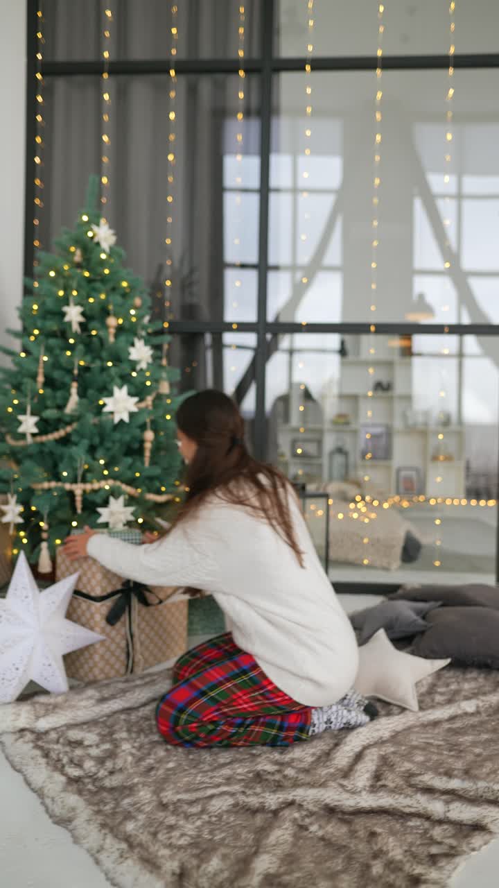 mujer abriendo regalos de navidad cerca del árbol