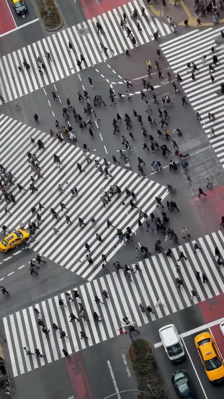 Aerial video view of a bustling crosswalk with people crossing in all directions