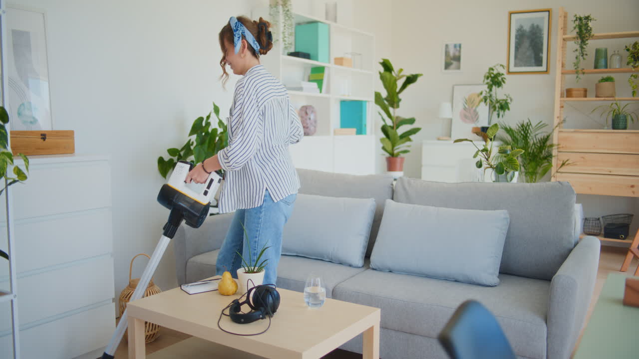 무선 진공청소기를 가진 웃는 여자