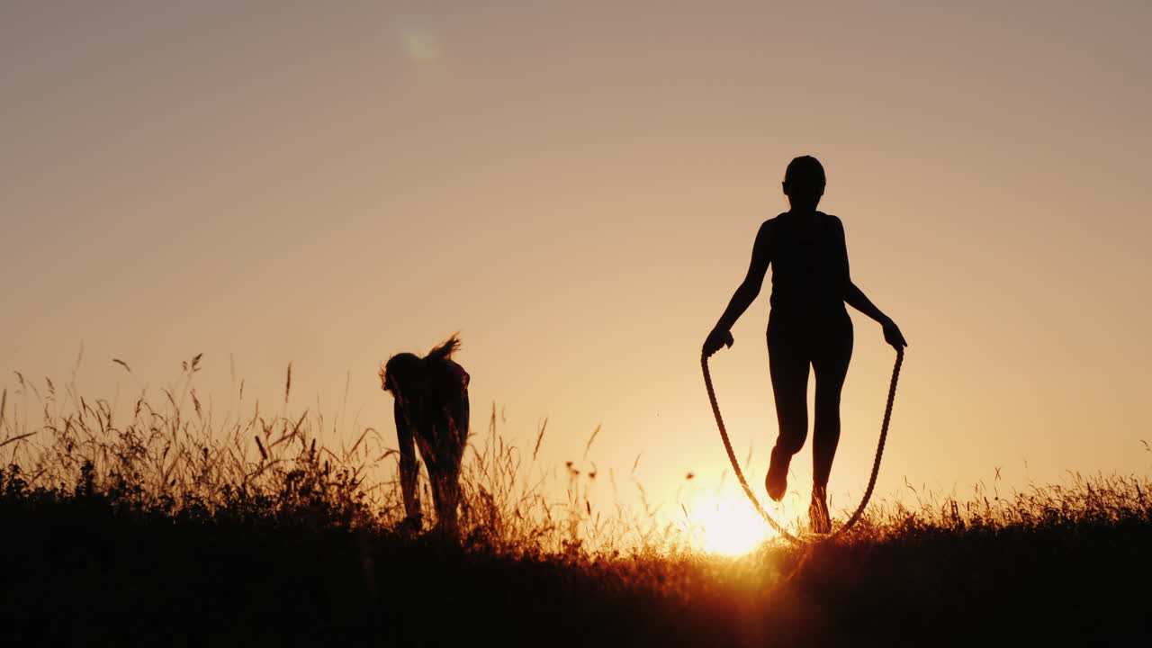 신선한 공기 속에서 훈련 - 석양에 밧줄을 뛰어넘는 여성의 실루엣