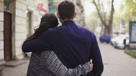 vista de fondo de una joven y hermosa pareja caminando por la calle abrazándose y hablando. cita romántica