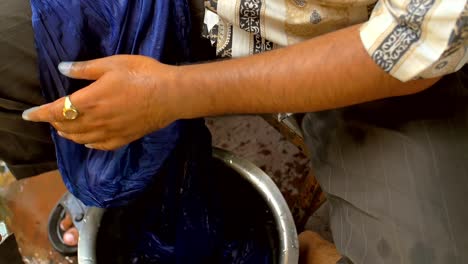 Man-Dyeing-Clothes-Next-to-Pots-of-Pigment