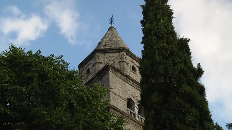 Restricted view of Church tower in the background behind trees, village of Plomin, Croatia