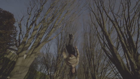parkour backflip in a tree lined park