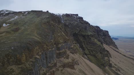 Aerial-landscape-view-of-icelandic-mountain-tops,-with-melting-snow,-on-a-moody-evening