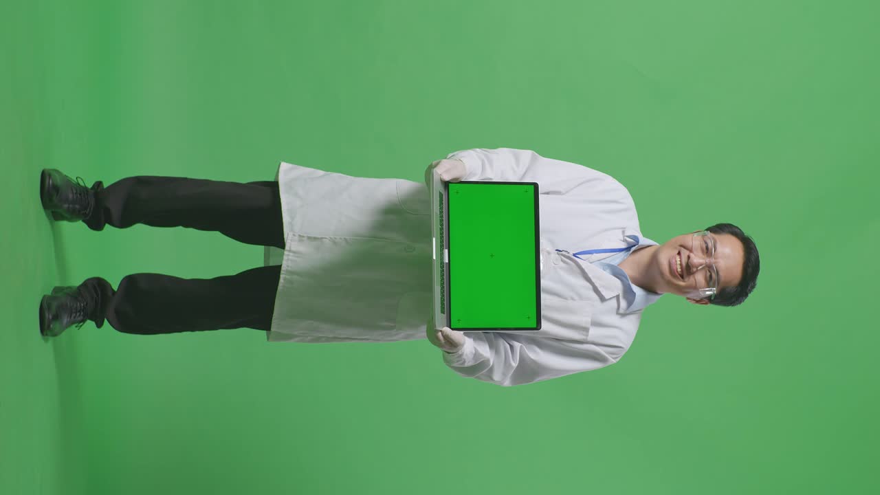 Full Body Of Asian Man Scientist Smiling And Showing Green Screen Laptop To Camera While Standing On Green Screen Background In The Laboratory