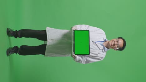 full body of asian man scientist smiling and showing green screen laptop to camera while standing on green screen background in the laboratory