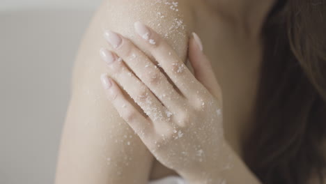 woman applying salt scrub to her shoulder