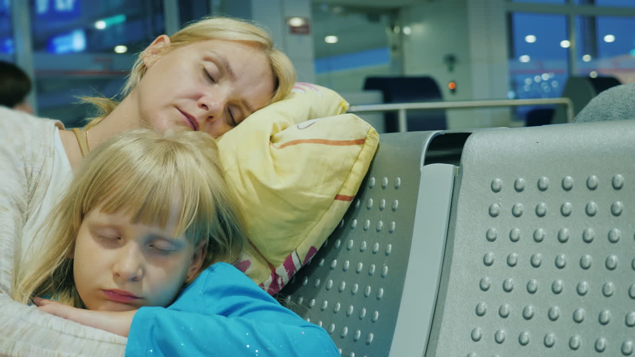уставшая женщина с ребенком спит в терминале аэропорта задержка или отмена рейса понятие