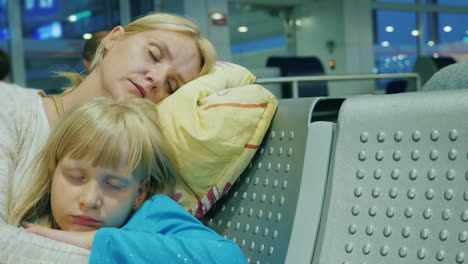 tired woman with a child sleep in the airport terminal delay or cancellation of voyage concept