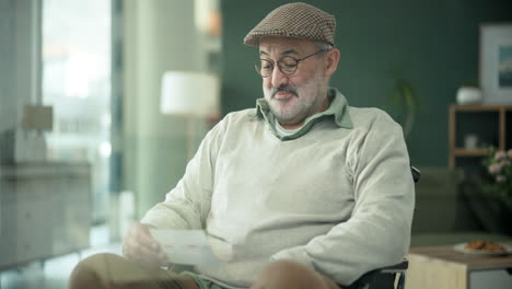 older man reading a letter in a wheelchair