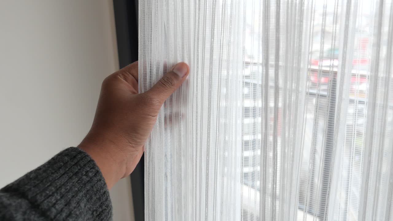 Person öffnet einen weißen Vorhang