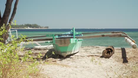 Pequeño-Barco-Tendido-En-La-Orilla-De-Una-Playa-De-Arena-Con-Aguas-Cristalinas