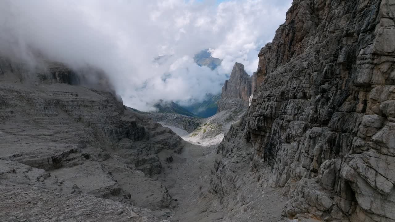 vuelo aéreo lento entre las montañas rocosas de brenta en dolomita durante el día brumoso - vuelo al valle brumoso de italia