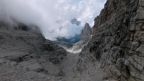 Slow-aerial-flight-between-rocky-Brenta-Mountains-in-Dolomite-during-foggy-day---Flight-into-misty-valley-of-Italy