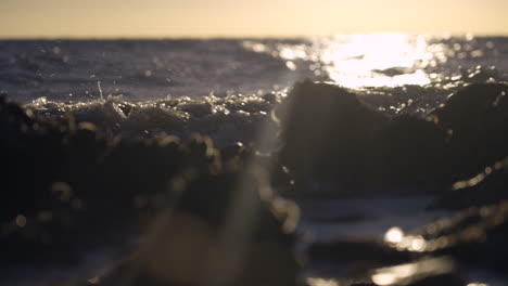 wide shot of waves crashing on rocks with early morning sun