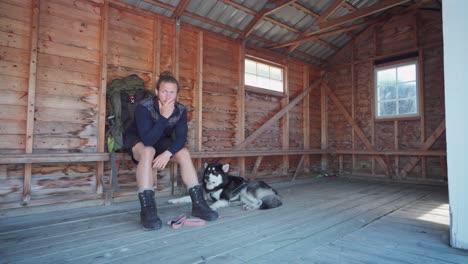 man petting dog lying on the floor while waiting for the ferry at wooden terminal