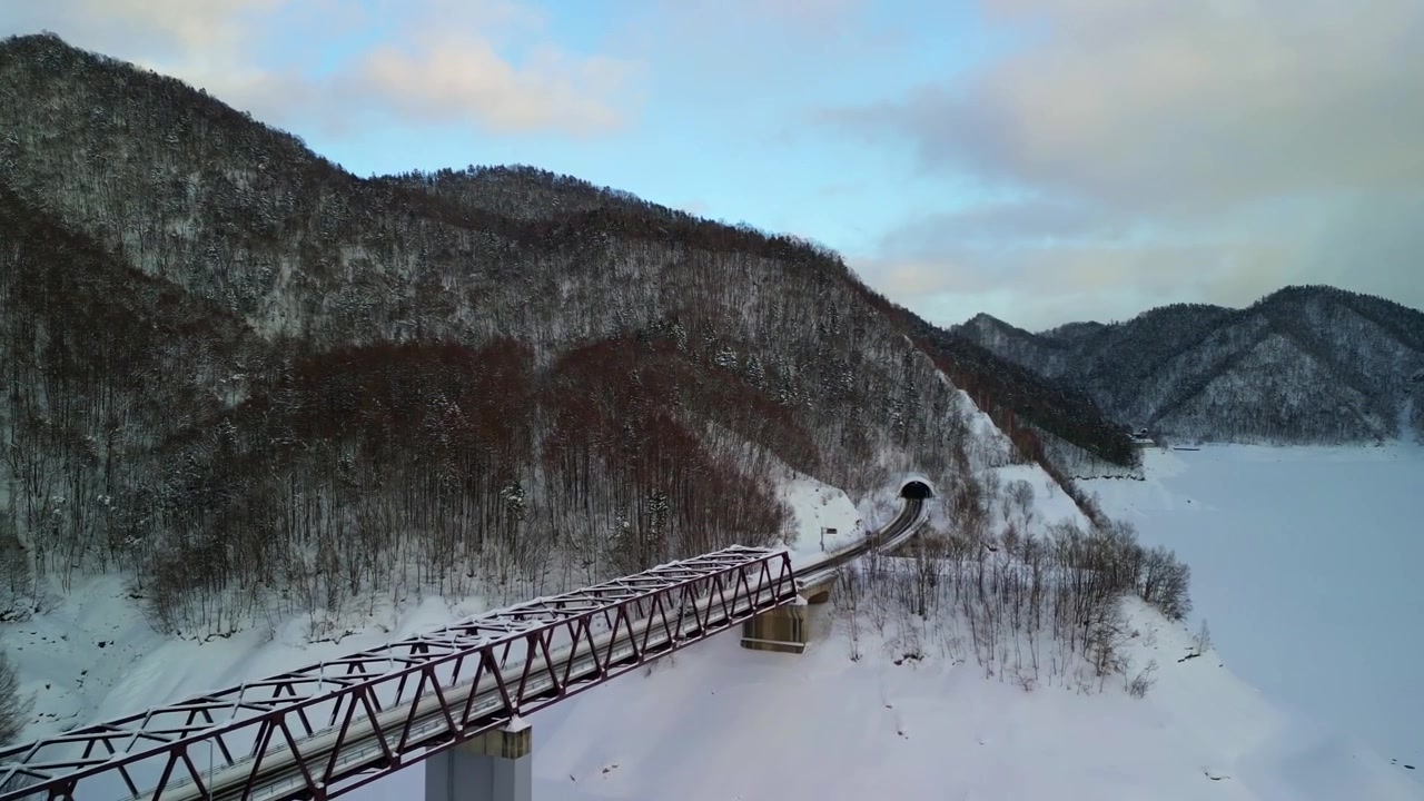 Szczegółowa inspekcja lotnicza zabytkowego mostu kolejowego w kształcie łuku, otoczonego głębokim śniegiem Hokkaido