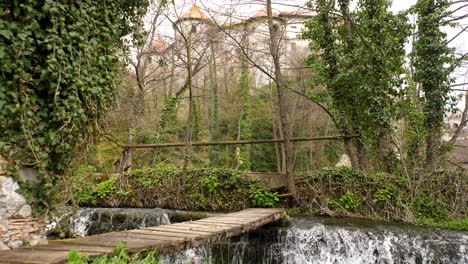 static low-angle shot of a wooden bridge across a small waterfall on the krka river