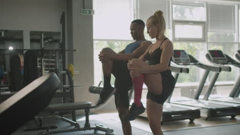 side view of caucasian female monitor and an athletic african american man in the gym.