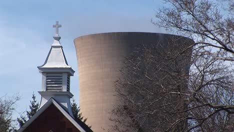 La-Cámara-Se-Enfoca-En-El-Campanario-De-Una-Iglesia-Y-Una-Planta-De-Energía-Nuclear-En-Las-Proximidades.