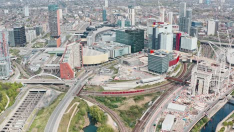 pan down dolly forward drone shot of dlr and london overground train in stratford city