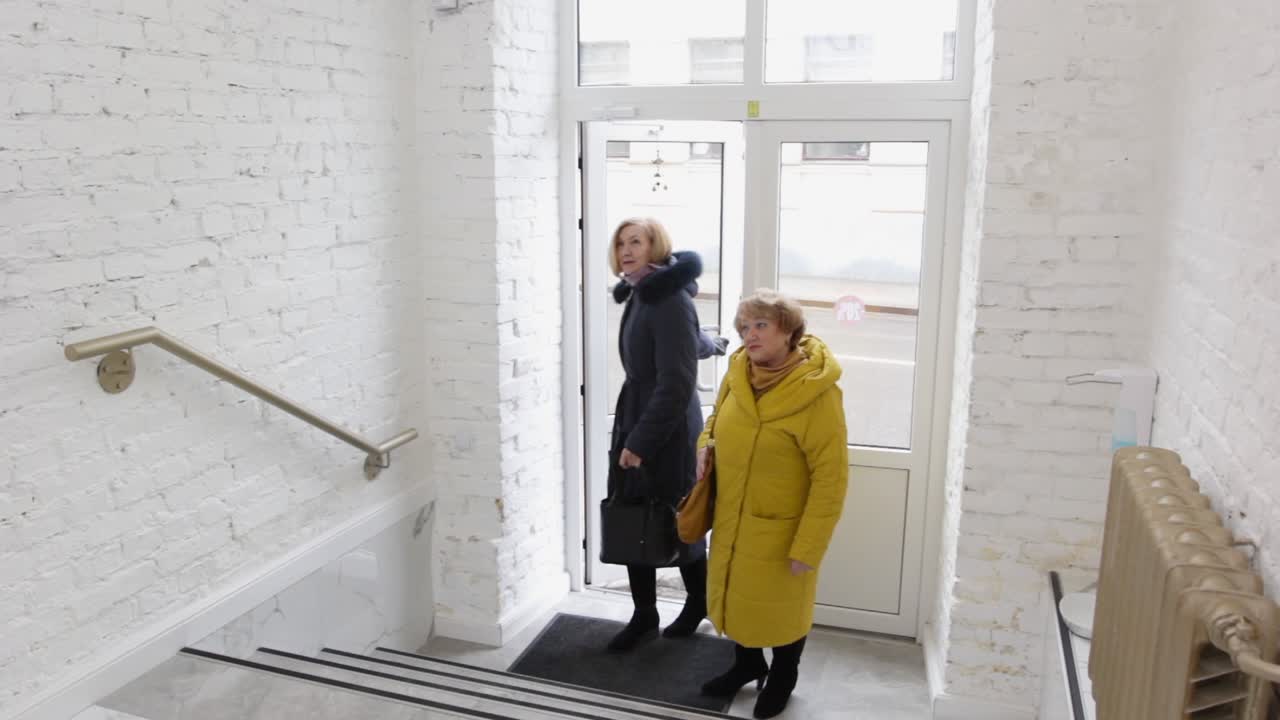 우아한 노인 친구들이 문을 열고 패션 부티크에 들어갑니다.