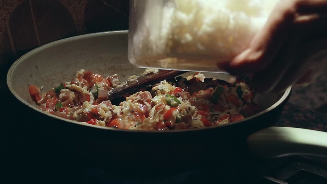 Adding rice to a pan of sauteed vegetable cubes and scrambled eggs for a simple yet healthy vegetarian fried rice recipe, home cooking in candid daily life