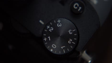 Finger-adjusting-exposure-compensation-control-wheel-on-photo-camera,-close-up