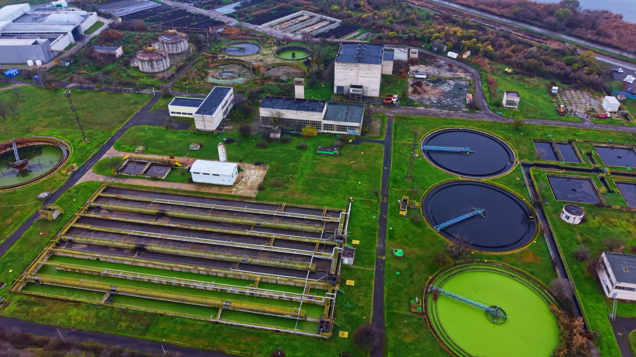 Facility for water treatment located in an industrial area showing circular tanks and surrounding greenery during the day