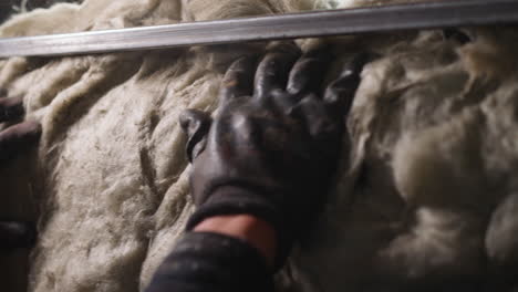 employee in gloves adjusts glass wool at construction site