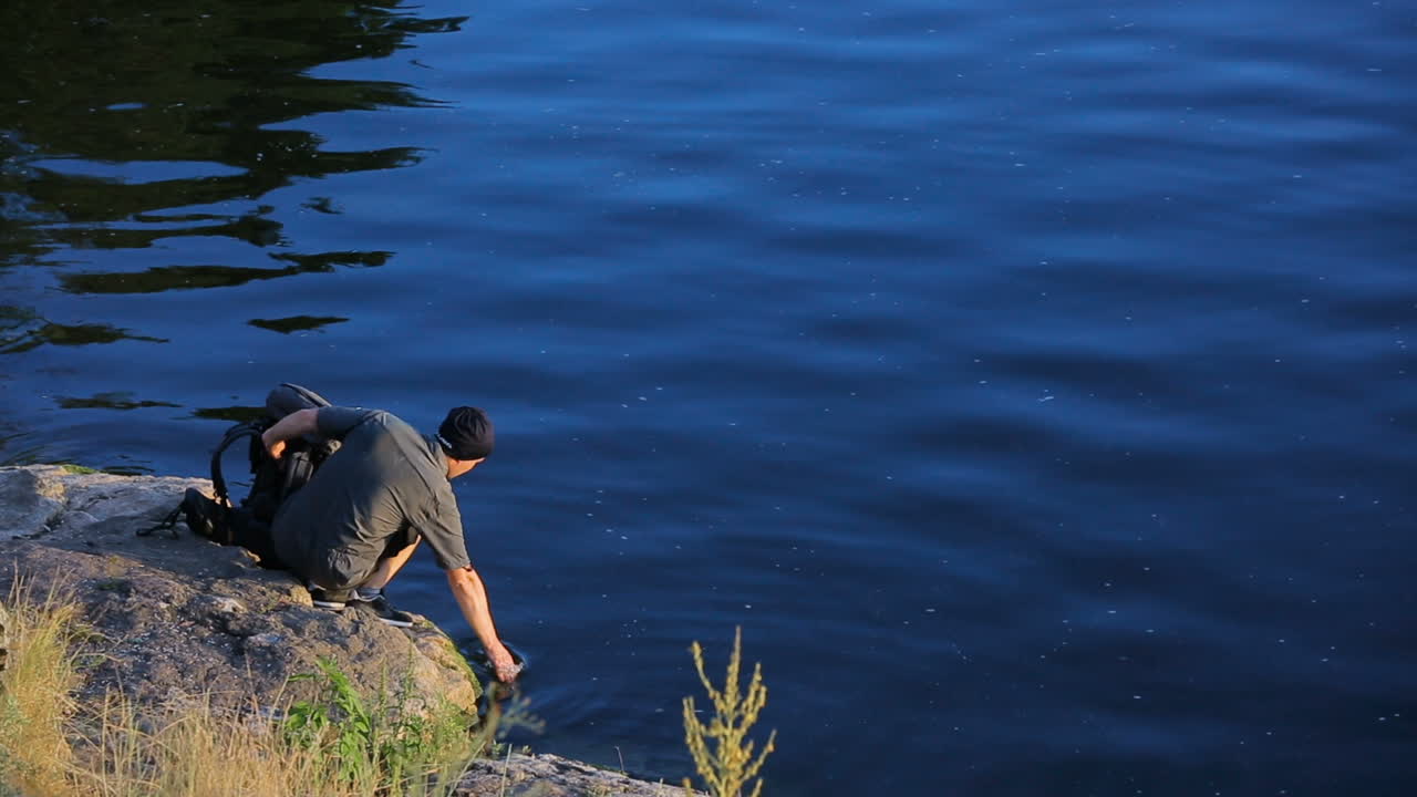 Adult Hiking With Backpack. Rear view of adult man walking down the hill at sunset