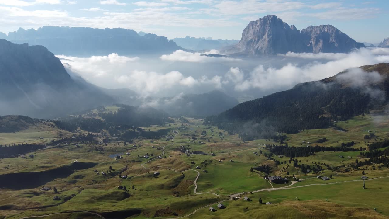 vista aérea de una pequeña civilización en el suelo en medio de las montañas de dolomitas con la niebla sobre las casas