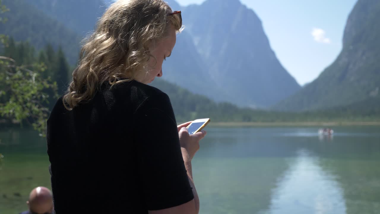 señora turista rubia en su teléfono mientras está de vacaciones en un hermoso entorno natural