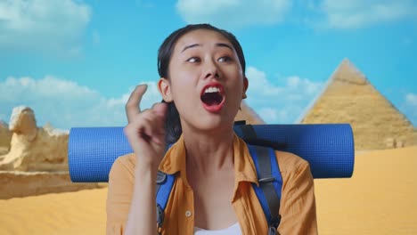 close up of asian female hiker with mountaineering backpack thinking about something and looking around then raising her index finger while traveling in pyramid of giza
