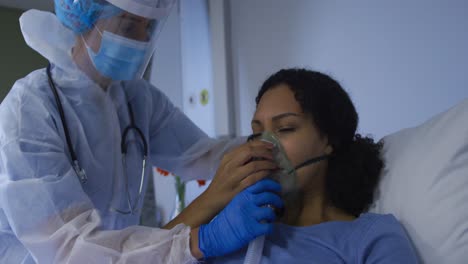 Doctora-Caucásica-Poniendo-Un-Ventilador-Con-Máscara-De-Oxígeno-A-Una-Mujer-Afroamericana-En-El-Hospital