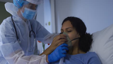 doctora caucásica poniendo una máscara de oxígeno en una mujer afroamericana en el hospital