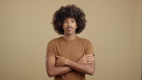man with afro hair and mustache standing with arms crossed