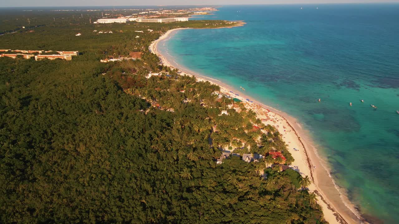 Circling around the point where the dense Mexican forest land meets the Caribbean sea waters on the iconic beachfront of Playa Paraiso in Tulum, Mexico