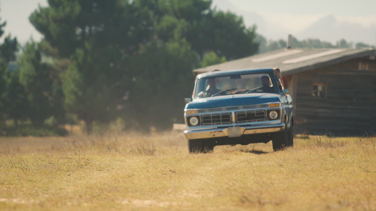amigos conduciendo una camioneta a través del campo en un viaje por carretera con la cabina en el fondo