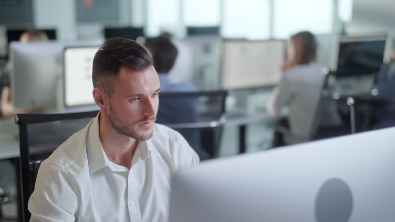 Portrait of Young Entrepreneur in Open Space Office Working on Decktop Computer. Male Professional Typing on PC Keyboard. Portrait of Positive Business Man Looking at Computer Screen