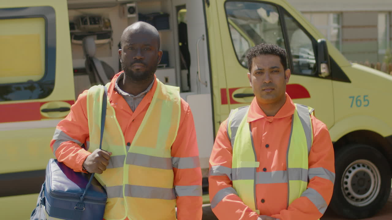 Medical Assistance With Blue Suitcase Is Outside The Ambulance Next To His Latin Work Colleague