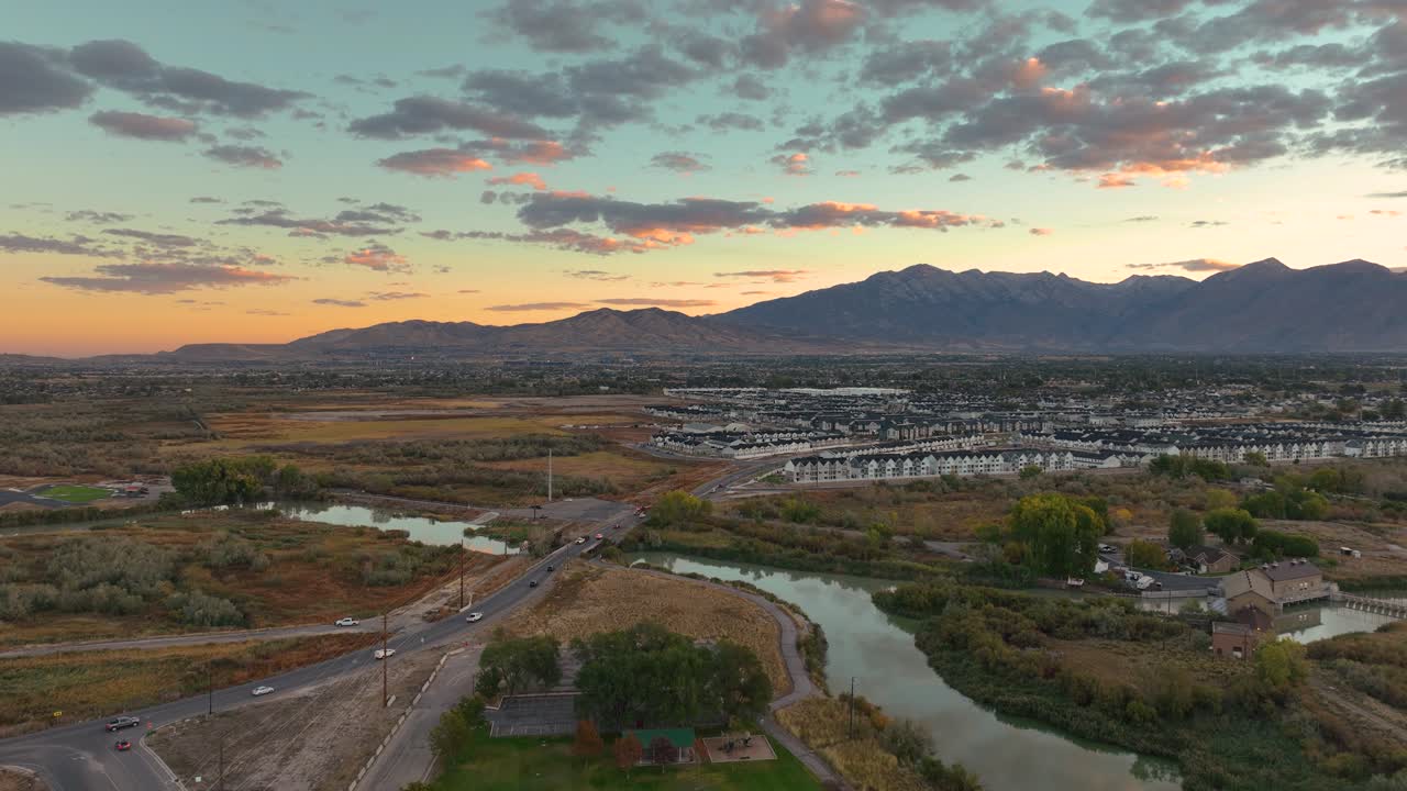 Vídeo de dron que captura la serena confluencia del río Jordán y el lago Utah en Saratoga Springs al amanecer. La calma del agua refleja el colorido cielo, creando una escena pintoresca.