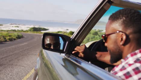 Hombre-Afroamericano-Ajustando-El-Espejo-Retrovisor-Lateral-Mientras-Está-Sentado-En-Un-Auto-Convertible