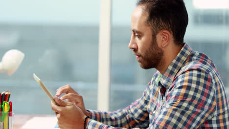 Casual-businessman-using-tablet-at-desk-