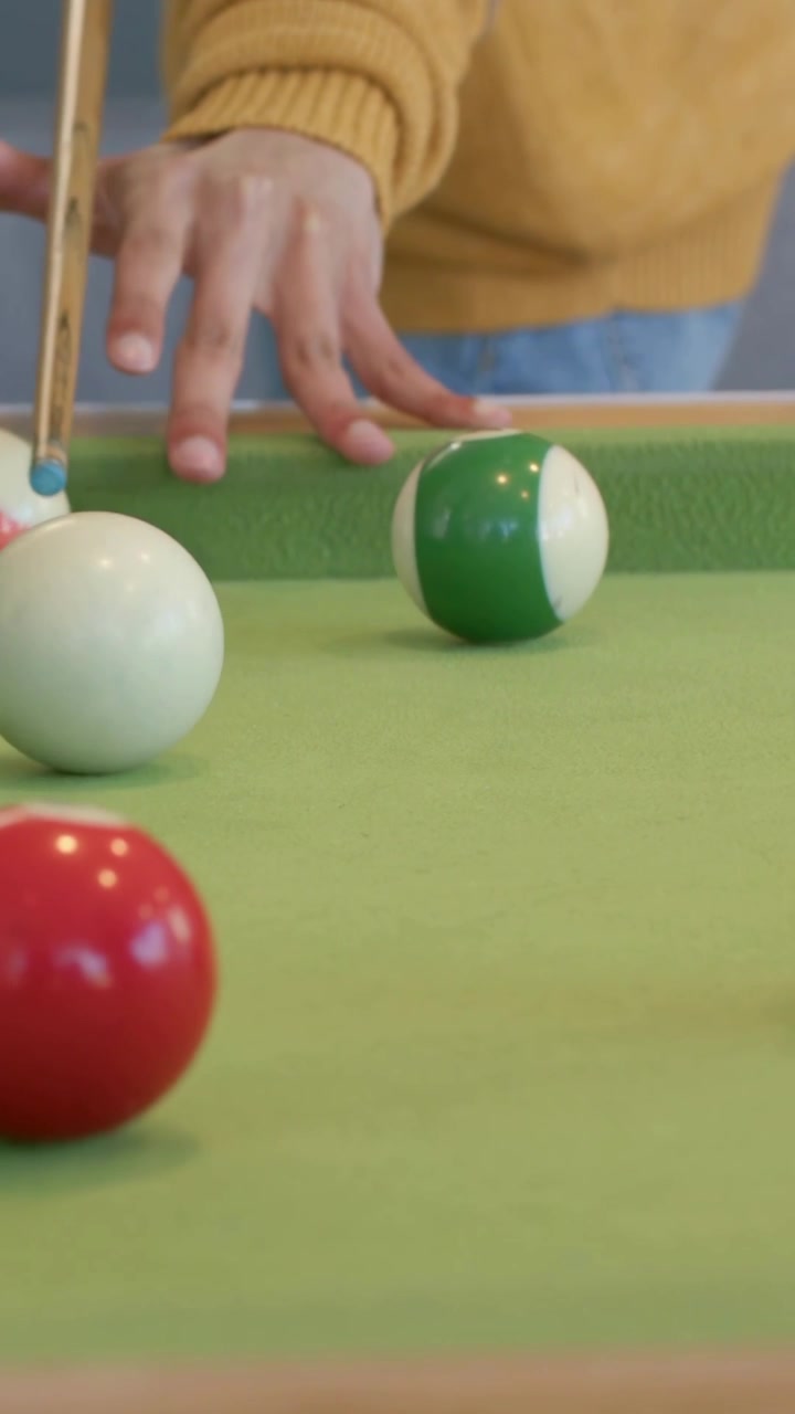 Man aligning and pulling cue, striking cue ball and sending target ball rolling right in sports
