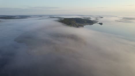Luftaufnahme-über-Den-Wolken-über-Insel-Und-Wald-Yttereneby-Naturschutzgebiet,-Nebel,-Naturlandschaft-In-Schweden