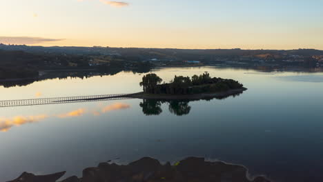 Aerial-shot-circiling-around-Aucar-island-in-Chile,-showing-the-golden-sky-at-sun-set